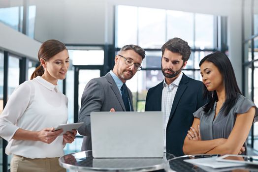 Hes got something to show them. a group of businesspeople gathered around a laptop in the office