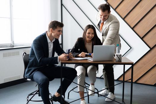 interaction of office employees during the working day at the table in front of a laptop.