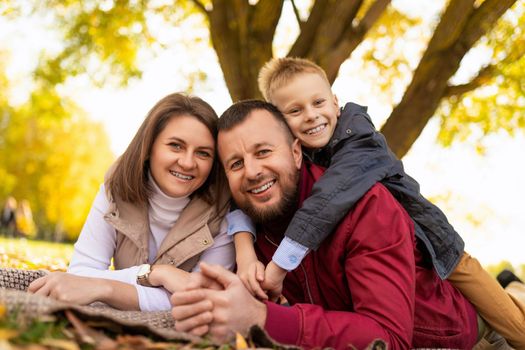 close-up portrait of a happy traditional family with a small child in a park on the ground.