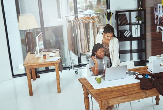 Giving her a few pointers. two young fashion designers working on a laptop