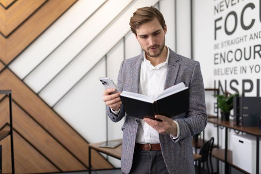 Businessman with a notepad in his hands by a mobile phone plans meetings and business events for the day.