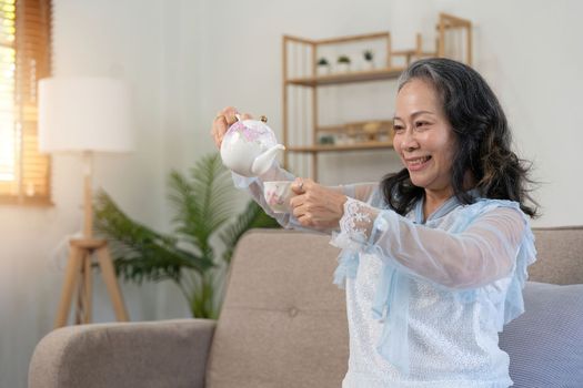 Happy old woman drinking healthy tea at home.