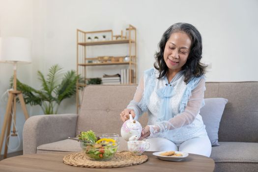 Happy old woman eating healthy food at home.