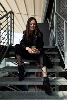 portrait of a successful independent ambitious female executive sitting on the steps with a cup of coffee with a wide smile.