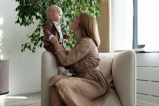 happy mother with her little child are sitting in a chair.