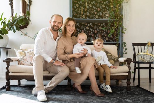 happy european family with two little boy children sitting on sofa in stylish room.