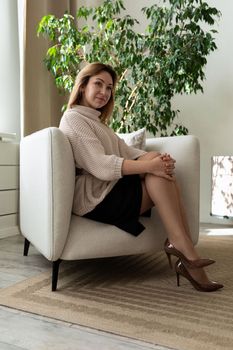 portrait of business stylish middle aged woman sitting in armchair looking at camera.