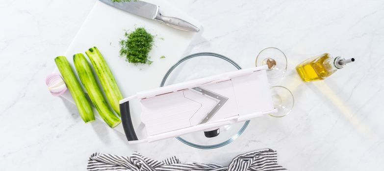 Flat lay. Slicing vegetables on slicer to make summer cucumber salad.