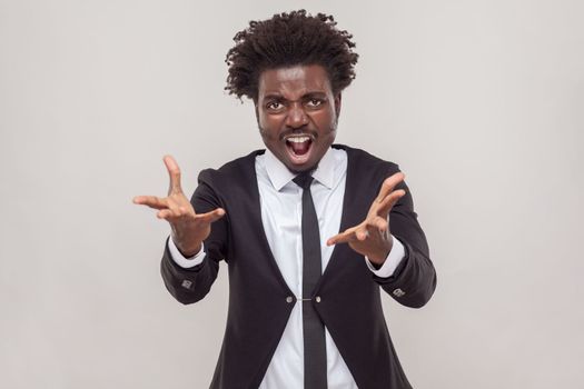 Emotional man yelling loudly, opens mouth broadly, feels desperate after finding out about tragic events, wearing white shirt and tuxedo. Indoor studio shot isolated on gray background.