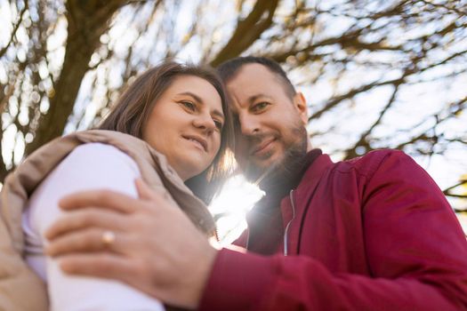 portrait of an adult traditional married couple with touching foreheads against the background of an autumn tree.