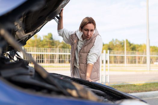 woman In Islam lousy car with the hood up trying to find the cause of the breakdown of the car.