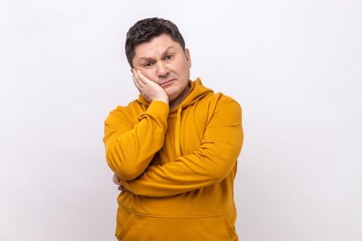 Depressed man feeling bored with tedious conversation, looking at camera with disinterest and apathy, indifferent to life, wearing urban style hoodie. Indoor studio shot isolated on white background.