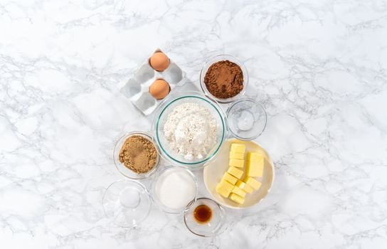 Flat lay. Measured ingredients in glass mixing bowls to bake chocolate cookies with chocolate hearts for Valentine's Day.