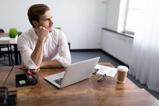 pensive young businessman fills out an insurance form on laptops in the office.