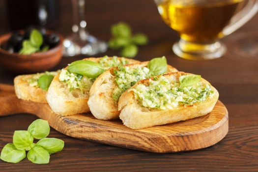 Delicious bread with garlic, cheese and herbs, red wine and olives on a wooden table.Copy space