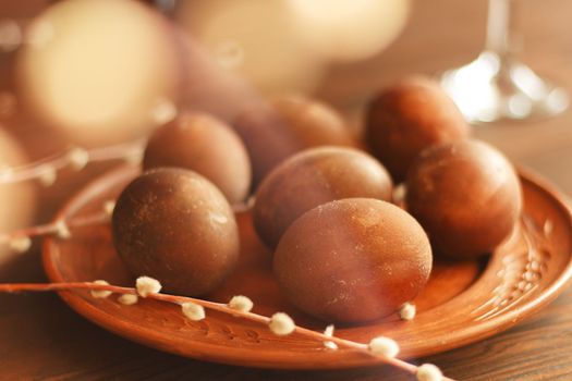 painted eggs on a plate with a sprig of willow on a wooden table. Easter celebration.