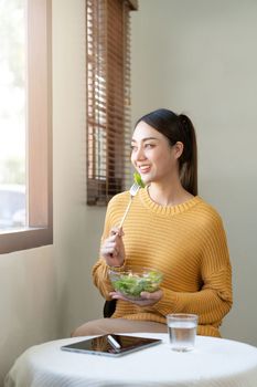 Delighted woman eating food for health at home.