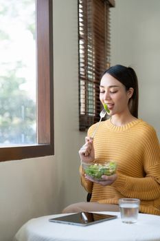 Delighted woman eating food for health at home.