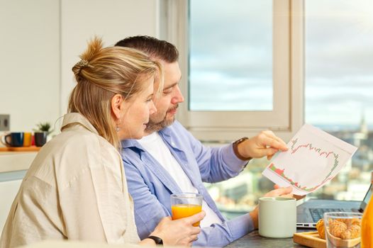 Happy couple working from home and having breakfast together. Breakfast together before leaving for work. Couple having breakfast while using laptop