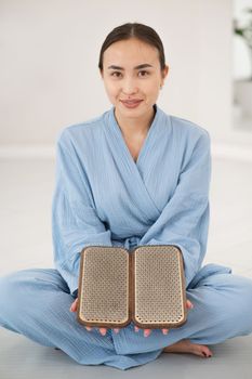 Asian woman sitting in lotus position on yoga mat and holding sadhu boards