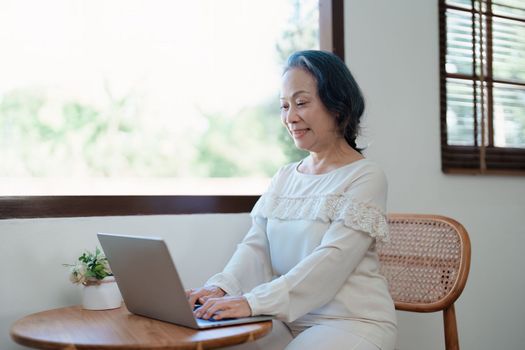 Portrait of an elderly Asian woman in a modern pose working on a computer