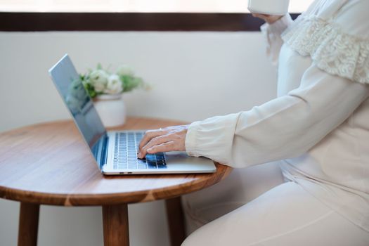 Portrait of an elderly Asian woman in a modern pose working on a computer