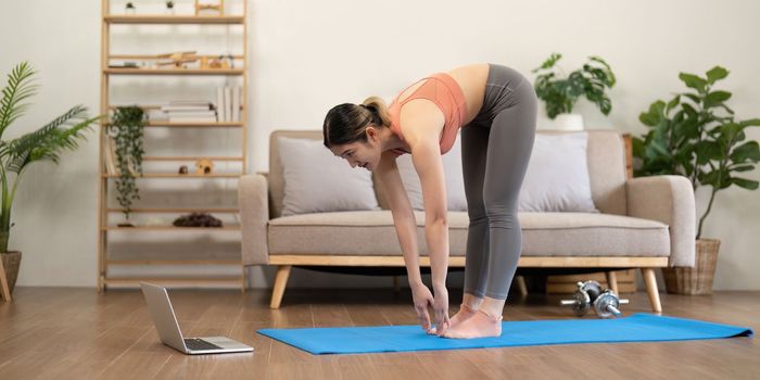 Young woman Exercising At Laptop Having Online Training At Home.