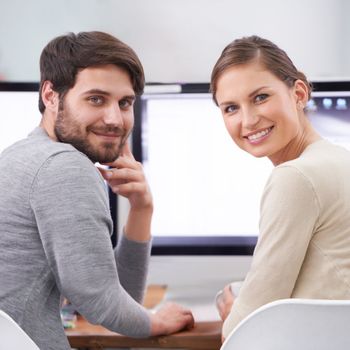 What a dynamic duo. Portrait of two smiling young professionals at their desk