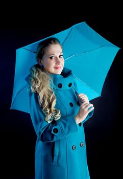 young girl in coat with blue umbrella