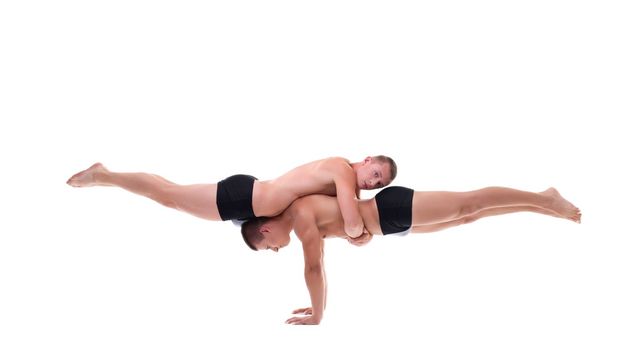 Young men practicing acrobatic balance isolated on white