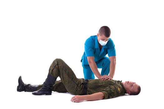 Rescuer makes first aid for soldier with heart attack, isolated on white