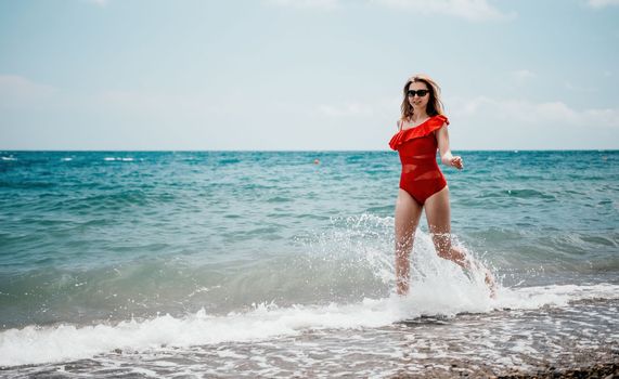 Young happy woman walks carefree on the seaside. Happy lady in red bikini. Portrait beautiful young woman relax smile around beach sea ocean in holiday vacation travel trip.