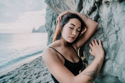 Portrait of cheerful female climber ascending a rock. The athlete girl trains in nature. Woman overcomes difficult climbing route.