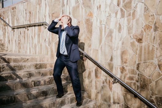 Portrait of a senior professional man in a suit with various problems. A middle-aged businessman with a briefcase descends the stairs.