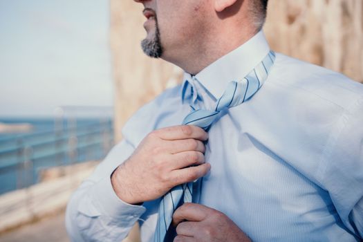 Close up of Man Adjusting Tie of Suit. Businessman in white shirt straightens his tie, close-up.
