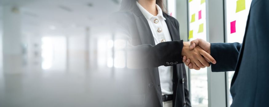 Business people handshake in corporate office in widen view showing professional agreement on a financial deal contract.