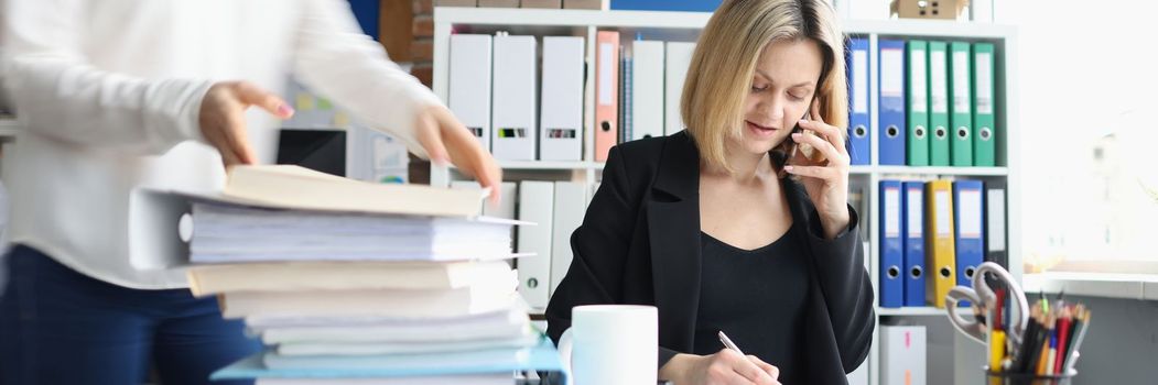 Businessman talking on phone secretary taking documents in office. Working atmosphere in office concept