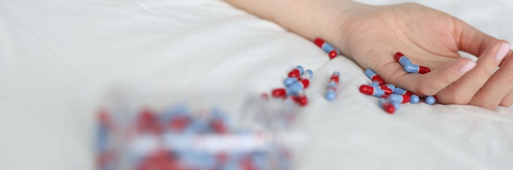 Woman hand after overdose of medical pills on bed. Medical consequences of abuse of sleeping pills concept