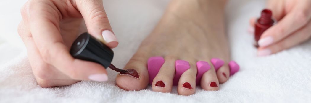 Woman makes herself pedicure on white background. Beautiful nail pedicure concept