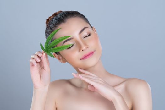 Closeup glamorous beautiful woman with soft make up and flawless smooth clean skin holding green leaf. Cannabis skincare cosmetic product for natural skin treatment concept in isolated background