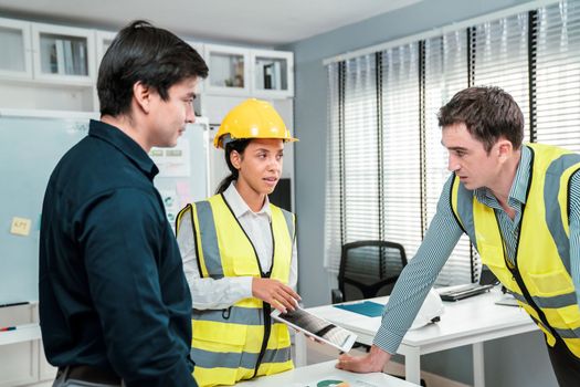 Engineers and competent employer discussing plans and blueprints together with tablet in the office. Concept of team contribution of ideas for engineering project.