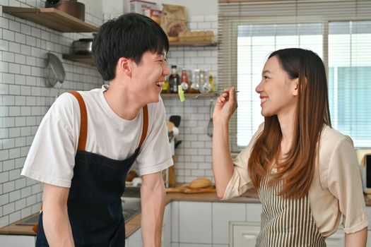 Cheerful asian woman having healthy lunch with her husband in kitchen. Concept of romantic relationship.