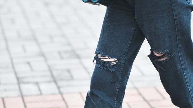 A girl in torn jeans walks through the city