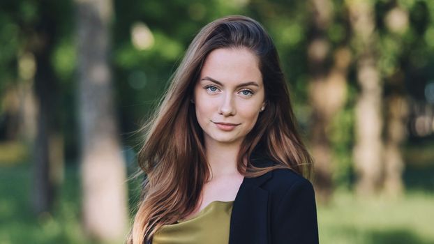 Portrait of a young business girl in a jacket in the park