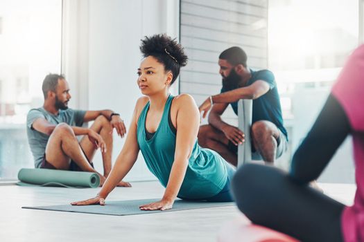 Yoga, fitness class and people exercise together for health, peace and wellness. Black woman and men group in health studio for holistic workout, cobra and body balance with zen energy or mindfulness.