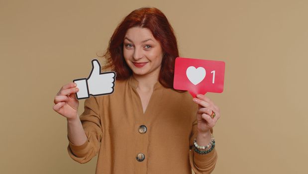 Like. Redhead woman raises inscription thumbs up banner thumbs up agrees with something, gives positive reply recommends advertisement likes good on social media. Young girl on beige studio background