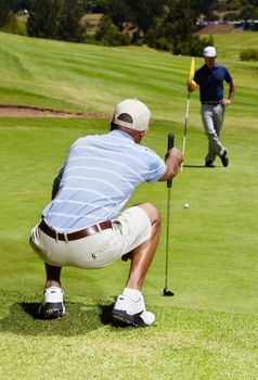 Eyeing the lay of the green. Rearview shot of a golfer eyeing up a long putt