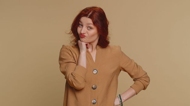 Sad redhead woman tired bored indifferent expression, exhausted of tedious story, not interested in communication talk, displeasure, uninteresting. Young girl isolated alone on beige studio background