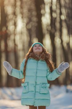 girl in a turquoise squat and a hat in a winter forest, shot vertically