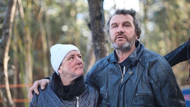 A homeless man and woman giving an interview in the winter in the woods